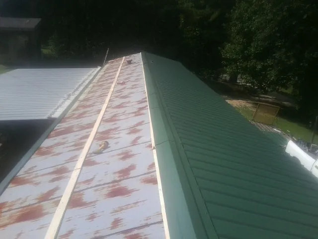 Old rusted panels beside newly installed green metal roofing — Wind Damage Roof Repair by Roofing Brothers in Flagtown