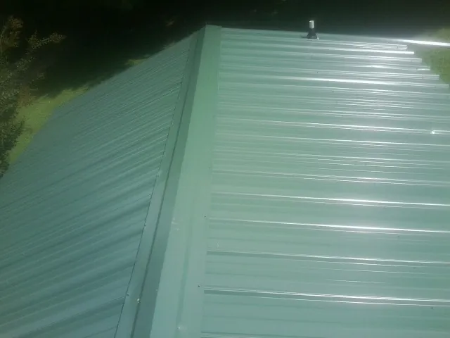 New green metal panels meeting at the ridge of a roof — Flat Roof Repair work by our crew in Flagtown