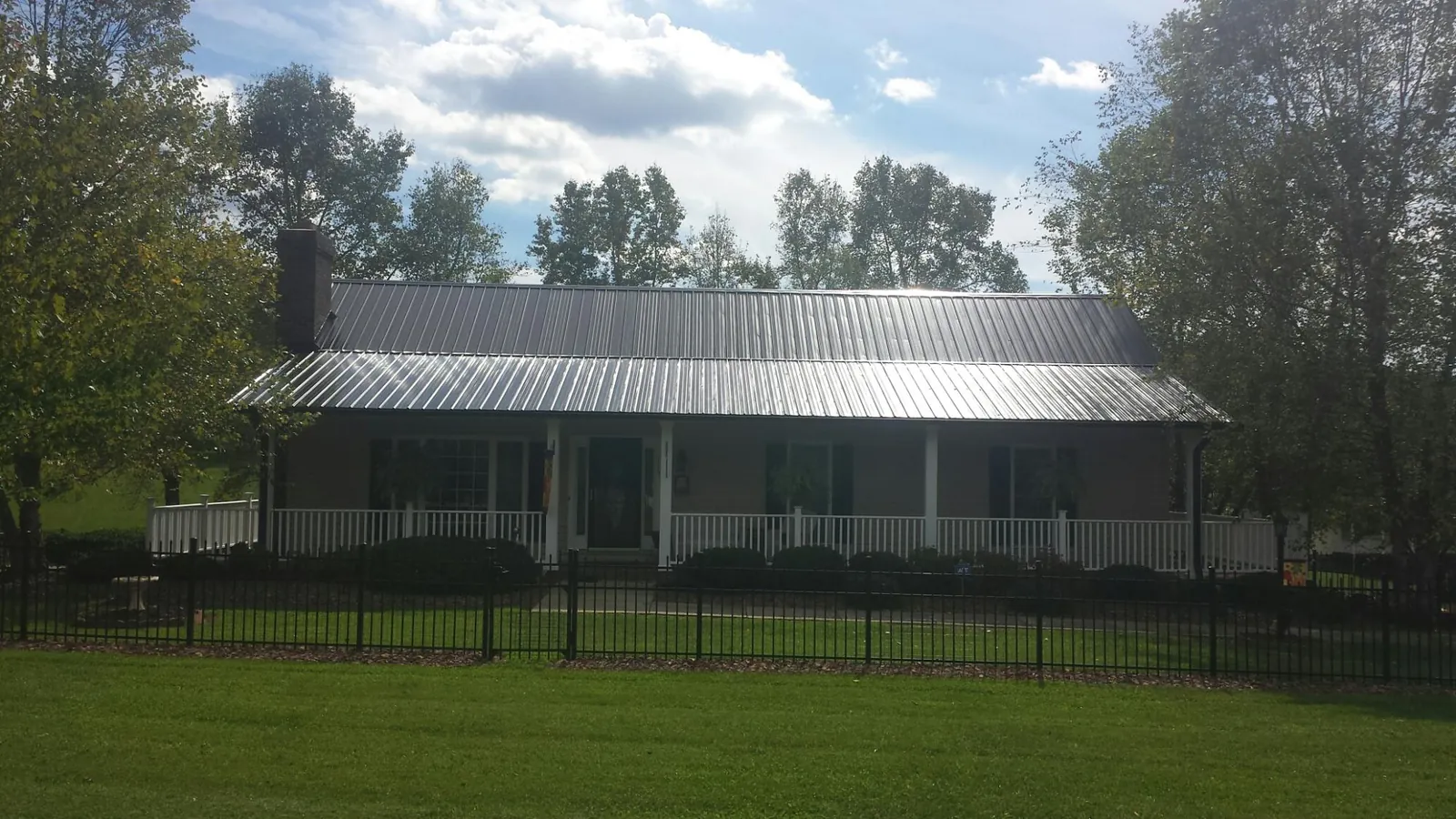 Gray metal roof on a brick ranch with a full width front porch — Gutter Guard Installation work by our crew in Flagtown
