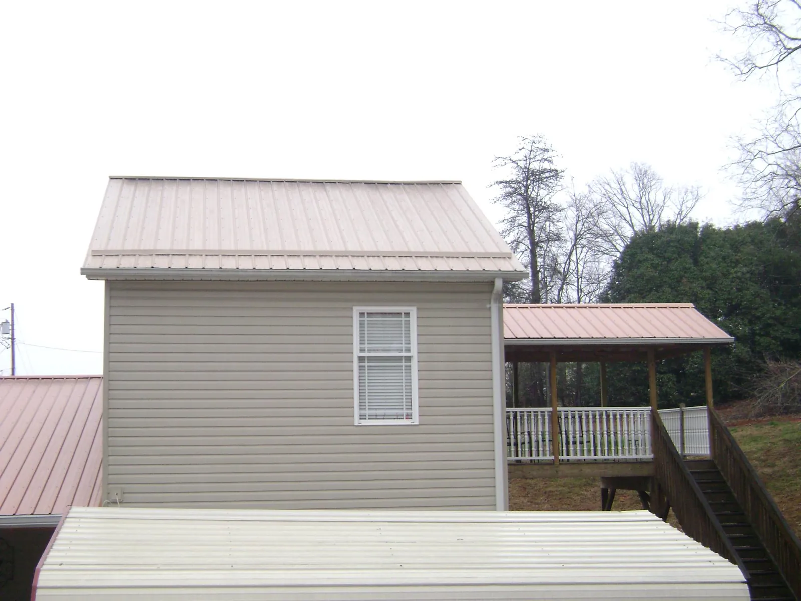 Tan metal roofs on a two story addition and attached porch, from a Roof Replacement job in Flagtown