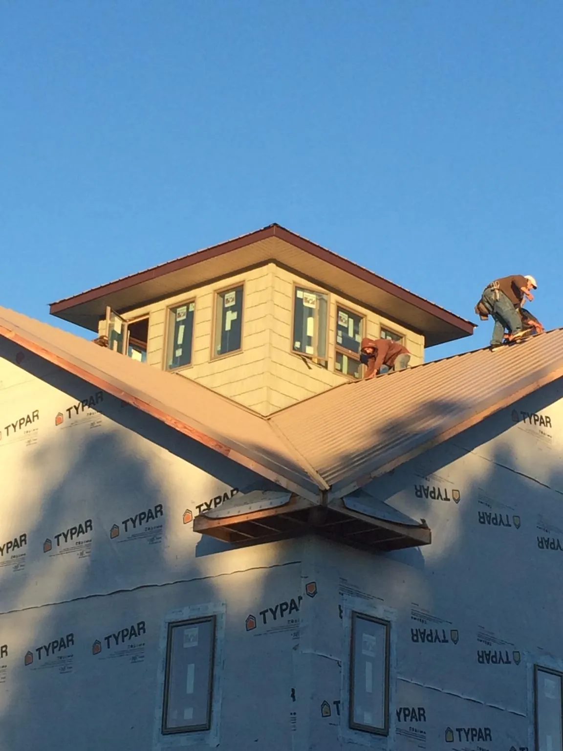 Roofers working around a rooftop cupola on a new metal roof at sunset — Roof Waterproofing in Flagtown by Roofing Brothers
